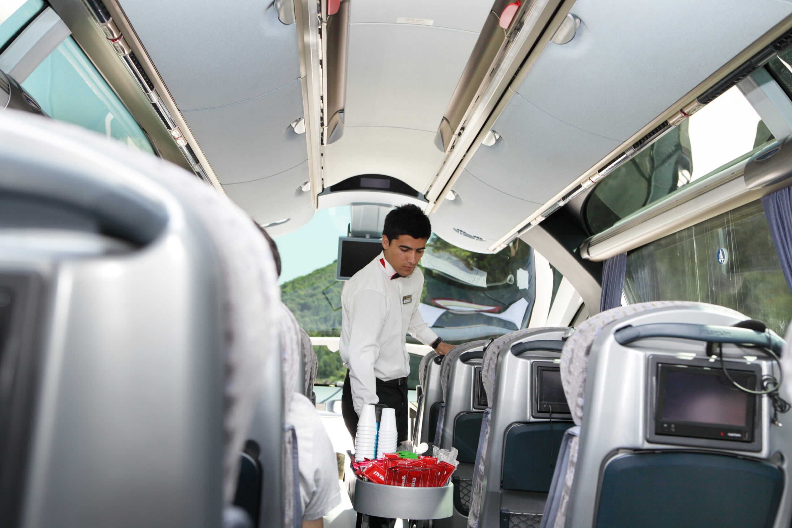 Steward serves drinks to passengers during the travel in charter empire luxury buss